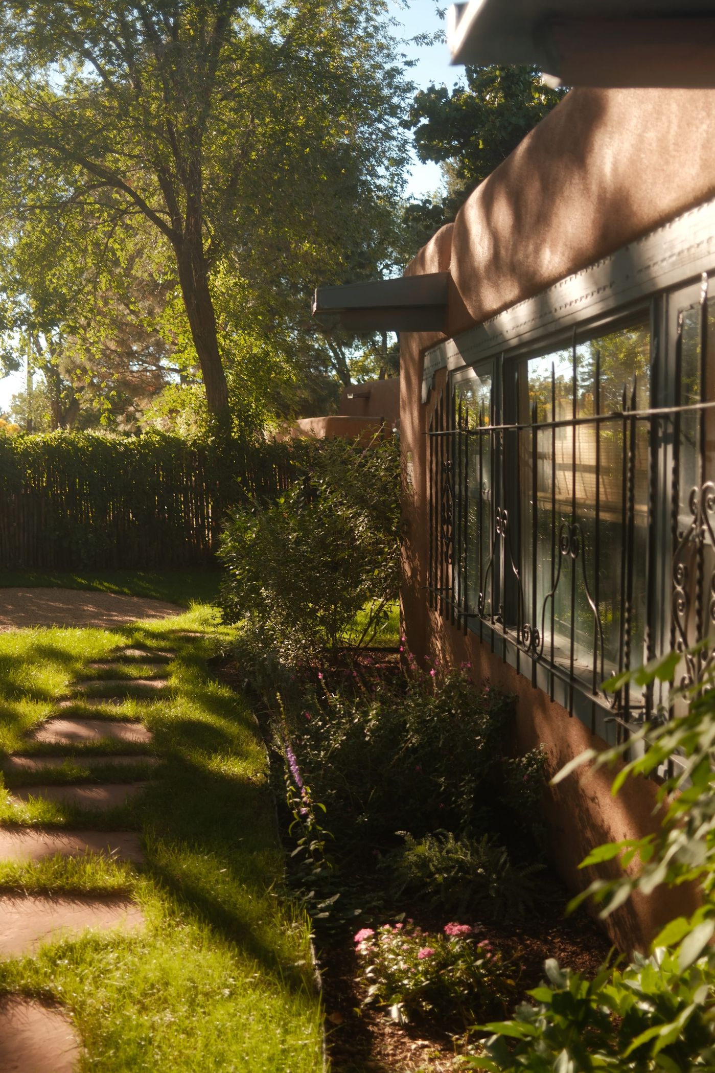 A stone path through the grass beside an adobe wall